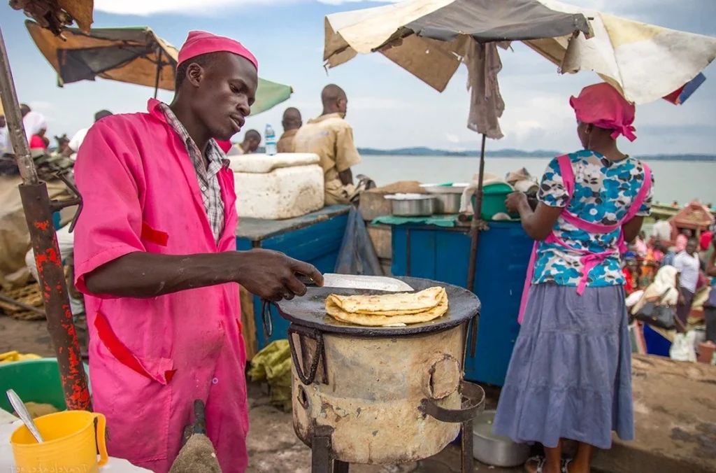 A street vendor in Uganda preparing a fresh, delicious Rolex, a rolled chapati filled with omelet and vegetables