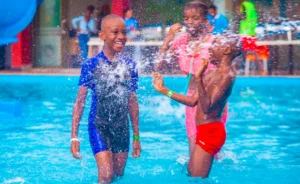 Families enjoying a day of Kampala kids activities at a water park, with children of all ages splashing and playing together in the refreshing water.