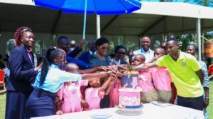 Nnaabegereka Sylvia Nagginda cutting cake with pupils of Masaka School of the Deaf, during the school's 20 year anniversary celebrations.