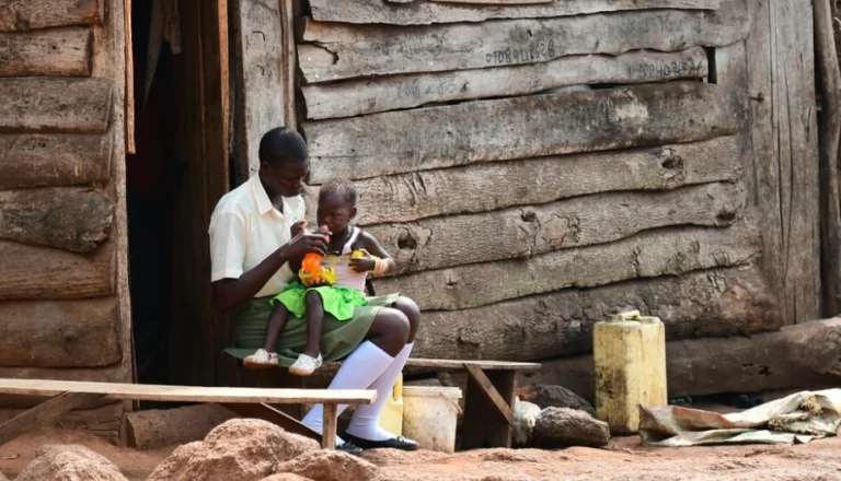 Young mother sitting alone, holding her baby with a distant look